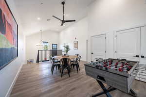 Playroom with high vaulted ceiling, hardwood / wood-style floors, and ceiling fan with notable chandelier