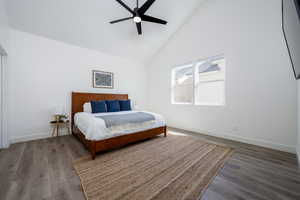 Bedroom with high vaulted ceiling, wood-type flooring, and ceiling fan