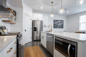 Kitchen featuring stainless steel appliances, white cabinetry, sink, extractor fan, and decorative backsplash