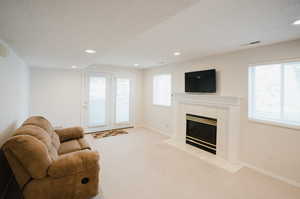 Carpeted living room featuring a tiled fireplace and a textured ceiling