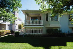 Back of property featuring a balcony and a yard