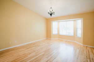 Unfurnished room featuring light hardwood / wood-style floors and a notable chandelier