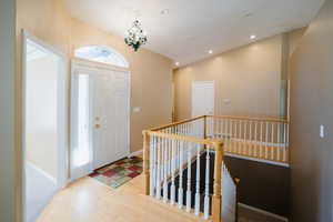 Foyer entrance with light wood-type flooring, a chandelier, and vaulted ceiling