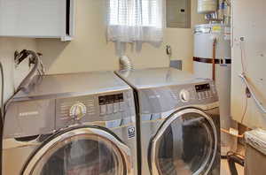 Clothes washing area featuring gas water heater, electric panel, and independent washer and dryer