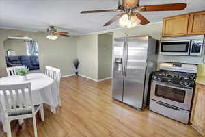 Kitchen with light wood-type flooring, ceiling fan, stainless steel appliances, and a textured ceiling