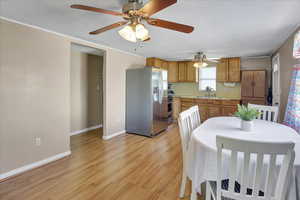 Dining space featuring a textured ceiling, ceiling fan, sink, and light wood-type flooring