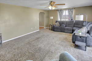 Living room featuring ceiling fan, carpet, and a textured ceiling