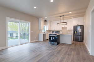 Kitchen with pendant lighting, stainless steel appliances, sink, hardwood / wood-style flooring, and white cabinets