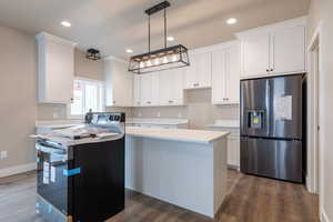 Kitchen with stainless steel fridge, electric range, a center island, and white cabinetry