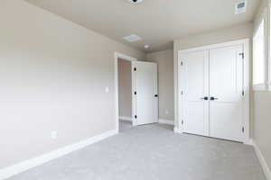 Unfurnished bedroom with light colored carpet and a closet