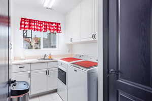 Washroom with washing machine and clothes dryer, cabinets, sink, and light tile patterned floors