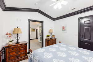 Carpeted bedroom with ceiling fan, crown molding, and vaulted ceiling