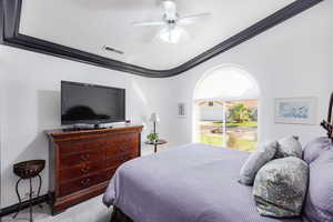 Bedroom featuring ceiling fan, light colored carpet, and ornamental molding