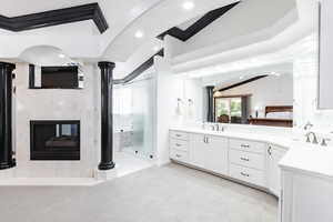 Bathroom featuring vanity, a multi sided fireplace, an enclosed shower, and vaulted ceiling with beams