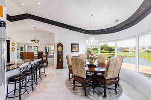 Dining area with a high ceiling, light tile patterned floors, a chandelier, and ornamental molding