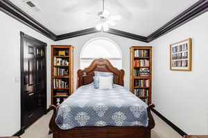 Carpeted bedroom featuring ornamental molding, vaulted ceiling, and ceiling fan