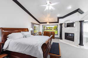 Carpeted bedroom with lofted ceiling, multiple windows, ceiling fan, and crown molding