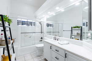 Full bathroom featuring shower / bath combination with glass door, vanity, toilet, and tile patterned flooring