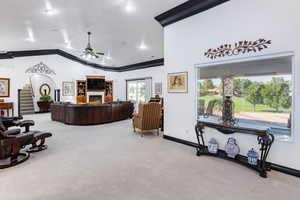 Carpeted living room with ceiling fan, ornamental molding, and vaulted ceiling