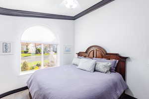 Bedroom with ornamental molding, light colored carpet, and ceiling fan