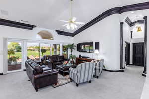 Carpeted living room featuring high vaulted ceiling, ceiling fan, and crown molding