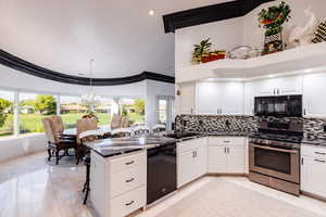 Kitchen featuring black appliances, plenty of natural light, a notable chandelier, and sink