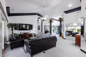 Living room with light colored carpet, ceiling fan, and high vaulted ceiling