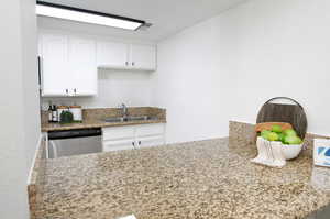 Kitchen with dishwasher, white cabinetry, and sink