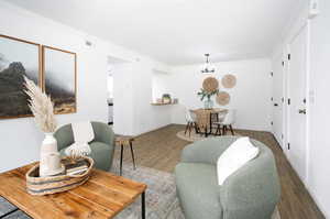 Living room featuring hardwood / wood-style flooring, an inviting chandelier, and ornamental molding