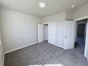 Unfurnished bedroom with dark colored carpet and a closet