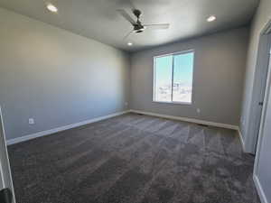 Carpeted spare room featuring ceiling fan and a textured ceiling