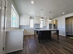 Kitchen with dark hardwood / wood-style flooring, pendant lighting, custom range hood, a center island, and white cabinets