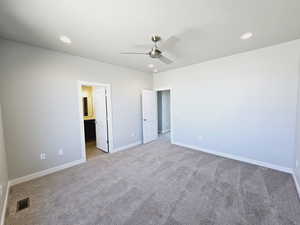 Unfurnished bedroom with light colored carpet, ceiling fan, and ensuite bath