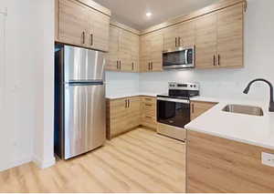 Kitchen featuring light hardwood / wood-style flooring, light brown cabinetry, sink, and appliances with stainless steel finishes