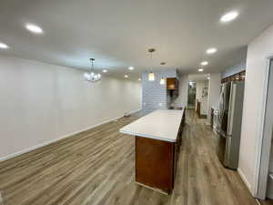 Kitchen featuring sink, pendant lighting, a chandelier, light hardwood / wood-style floors, and stainless steel refrigerator