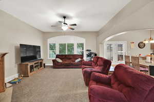 Living room with ceiling fan with notable chandelier and plenty of natural light