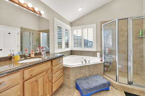 Master bathroom with vanity, vaulted ceiling, tile patterned floors, and plus walk in shower