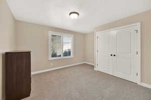 Bedroom featuring a textured ceiling, light colored carpet, and a closet