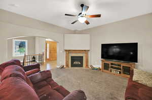 Carpeted living room featuring ceiling fan and a tiled fireplace