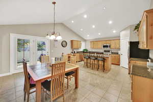 Dining area featuring high vaulted ceiling, a chandelier, and light tile patterned flooring