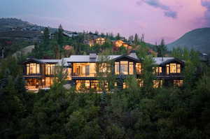 Back house at dusk featuring a balcony and a mountain view