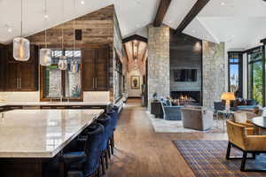 Interior space featuring beamed ceiling, high vaulted ceiling, a large fireplace, sink, and hardwood / wood-style flooring