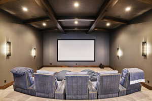 Carpeted home theater room with beamed ceiling