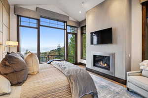 Bedroom with high vaulted ceiling, hardwood / wood-style flooring, and access to exterior