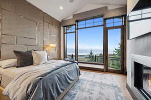 Bedroom featuring a water and mountain view, vaulted ceiling, and hardwood / wood-style floors