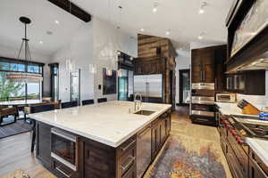 Kitchen featuring hanging light fixtures, light hardwood / wood-style flooring, sink, a spacious island, and built in appliances