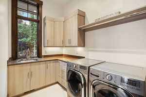 Laundry area featuring washer and dryer, cabinets, and sink