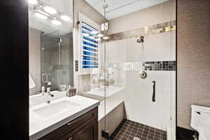 Bathroom with a shower with shower door, toilet, and vanity