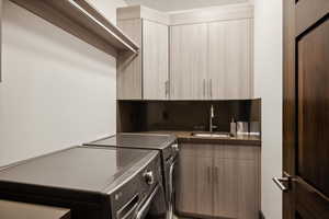 Clothes washing area with independent washer and dryer, cabinets, and sink