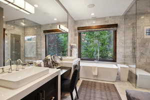 Bathroom featuring vanity, separate shower and tub, and tile walls